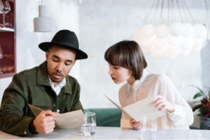 Two people looking at a restaurant menu.